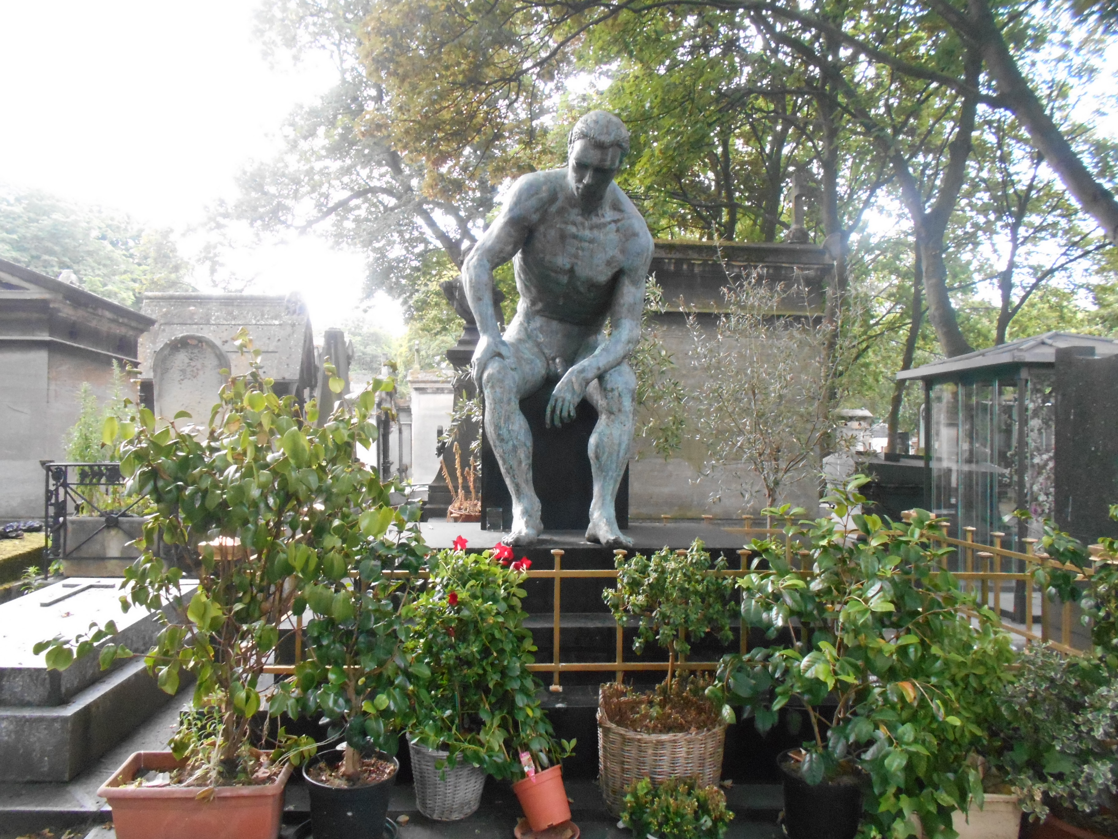 Sitzende und nackte Männerstatue auf den Friedhof Montmartre