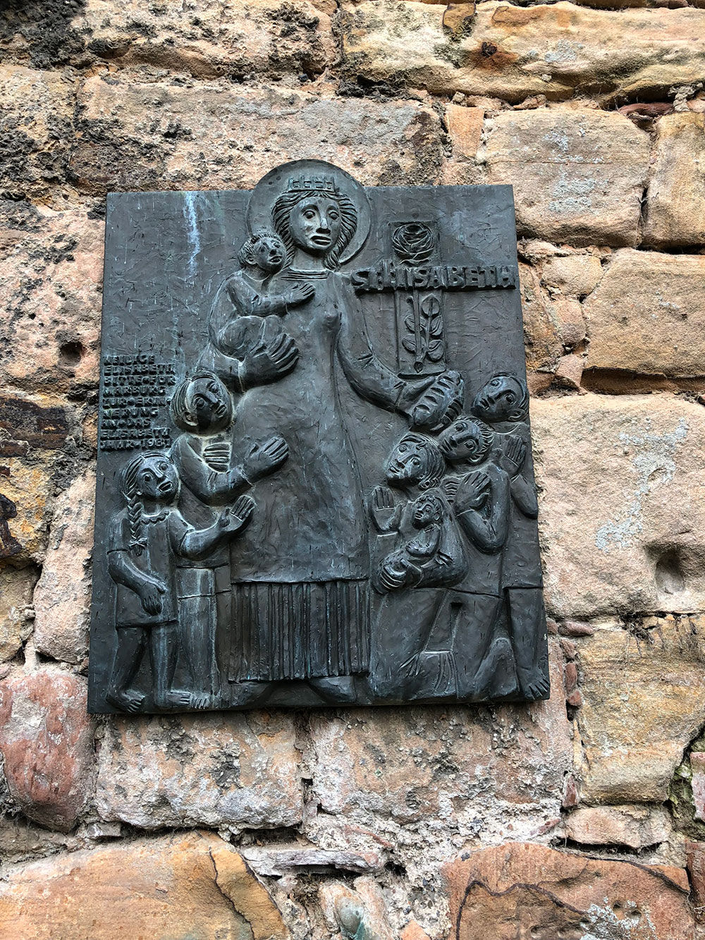 Bronzetafel für die heilige Elisabeth an einer Mauer