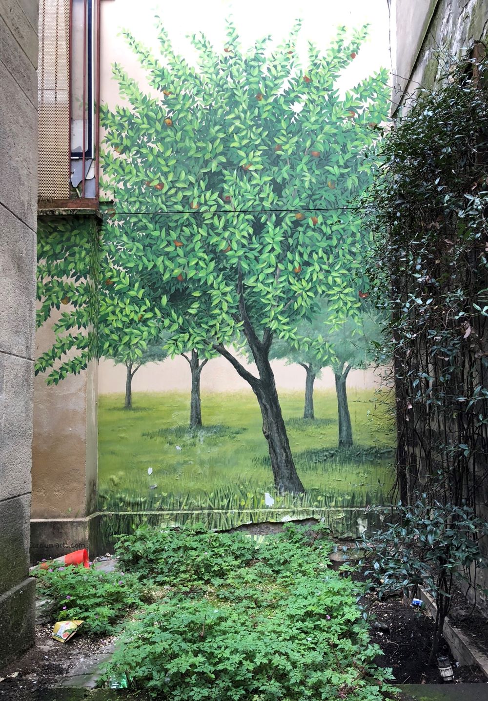 bemalte Hauswand mit Bäumen in einem Hinterhof im Pariser Quartier de la Roquette 