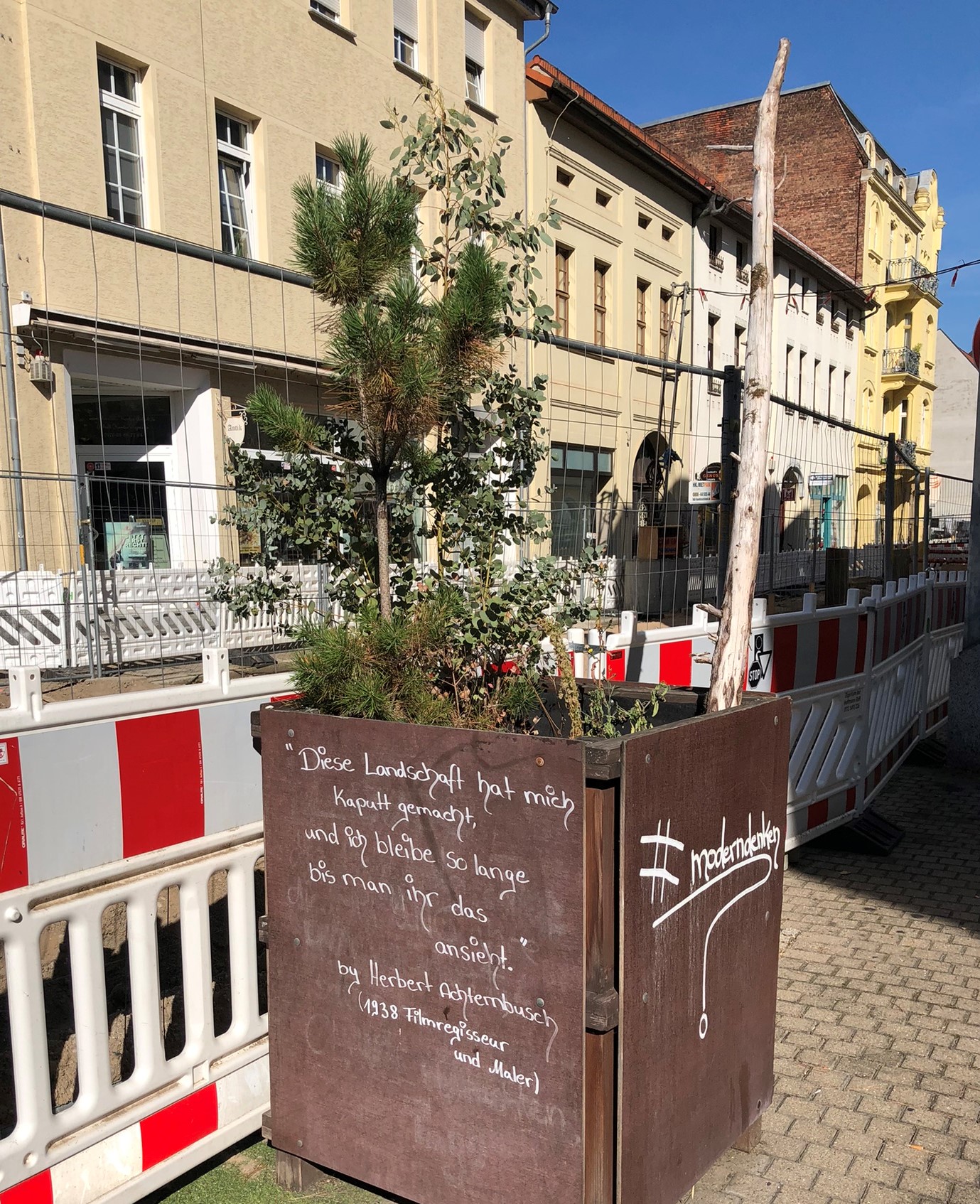 Blumenkübel vor dem Tobi ornot ToBe Restaurant in der Dessauer Johannisstraße mit dem Zitat "Diese Landschaft hat mich kaputt gemacht, ich bleibe solange bis man ihr das ansieht" von Herbert Achternbusch 